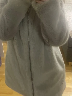 Ljusgrå pälsjacka från Pull&Bear - Säljer en supermjuk och fluffig ljusgrå pälsjacka från Pull&Bear.Perfekt för dig som vill ha en cozy och stylish vibe under kyliga dagar.