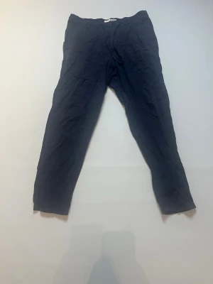 Mörkblå chinos från Selected Homme - Snygga mörkblå chinos från Selected Homme med klassisk rak passform. Byxorna har knapp och dragkedja i gylfen samt fickor både fram och bak. Materialet är mjukt och känns skönt mot huden, perfekt för en chill och stilren look.