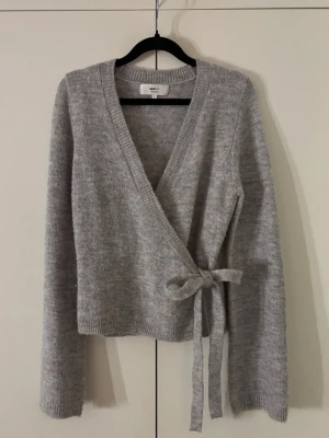 Stickad omlottttöja - En stickad omlotttröja från Gina tricot i storlek M. Supermjuk och mysig endast använd ett par gånger så i mycket bra skick.