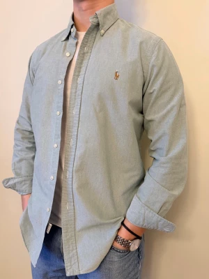 Ljusgrön Ralph Lauren skjorta - En stilren skjorta från Ralph Lauren. Second hand men i väldigt fint skick ✨ Tvättad och struken – redo att användas direkt.  Perfekt för både vinter och sommar, funkar både uppklätt och casual. Inga defekter och regular fit.  Storlek 👔: M Nypris 💰: ca 1 300 kr