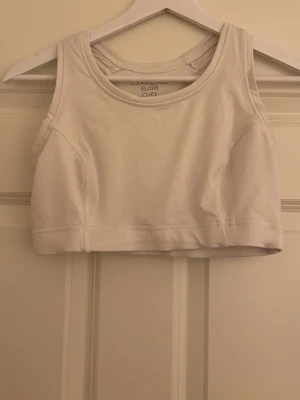 Vit träningstopp - Säljer en vit träningstopp i storlek S från stadium, den är väldigt kort och tajt och nästan aldrig använd