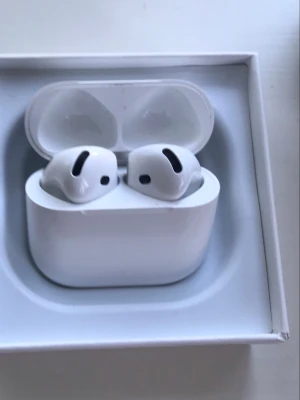 AirPods 4 - Apple AirPods  4i originalförpackning. Trådlösa hörlurar med laddningsetui, kompatibla med iPhone och andra Apple-enheter. Snygg design och bra ljudkvalitet. Produkten ser ut att vara i gott skick, med endast mindre yttre slitage på kartongen. Noice canceling helt nya