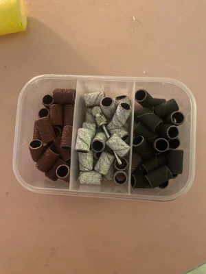 Sliprullar och metallfäste för nagelfil - Säljer ett set med sliprullar i brunt, silver och svart samt ett metallfäste för elektrisk nagelfil. Perfekt för att fixa naglarna hemma och få salongskänsla. Sliprullarna är cylinderformade och kommer i en praktisk plastlåda med tre fack.