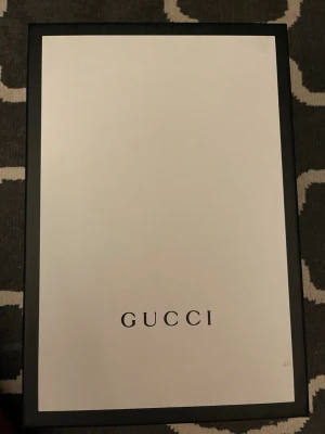 Gucci sneakers - Säljer ett par klassiska vita sneakers från Gucci med kardborreband. Skorna har Guccis ikoniska gröna och röda ränder på sidan, samt detaljer i grönt och rött på hälen. Tillverkade i skinn och kommer med originalkartong och dustbag.