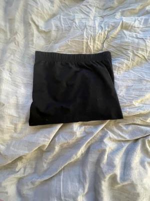 Svart kortkjol med resårmidja - Enkel svart kortkjol med rak passform och bekväm resår i midjan. Kjolen är helfärgad och har en stilren look som är lätt att matcha med olika toppar. Perfekt för dig som gillar minimalistisk stil.