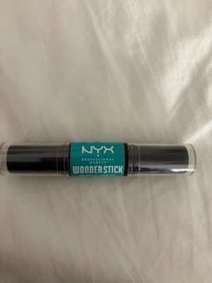NYX Wonder Stick contour highlighter duo - NYX Professional Makeup Wonder Stick är en dubbeländad contourstick med en krämig brun nyans för contouring och en ljus beige nyans för highlight. Perfekt för att skulptera och framhäva ansiktet. Smidig stickform i svart plast med turkos etikett. Testad en gång! Färg:Fair