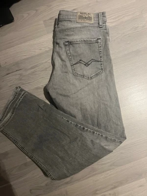 Replay ljusgrå jeans straight fit - Säljer ett par ljusgrå jeans från Replay med klassisk femficksdesign och raka ben. Jeansen har en snygg tvättad look och detaljerade bakfickor med Replay-logga på patchen. Perfekta till sneakers och hoodie för en chill stil.
