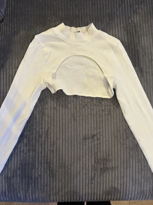 Vit ribbad topp ASOS - Säljer en vit croppad topp från ASOS DESIGN med lång ärm och hög hals. Har ej kommit till andvändning 