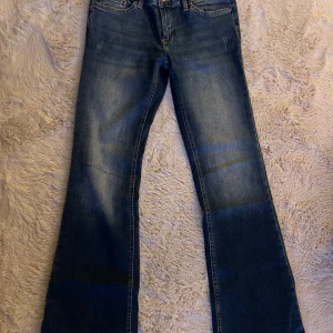 Blå bootcut jeans från ONLY - Säljer ett par klassiska blå jeans från ONLY i bootcut-modell. Jeansen har normal passform, fem fickor och snygga slitningar framtill. Tillverkade i jeansmaterial med gul kontrastsöm. Perfekta för dig som gillar en tidlös look.