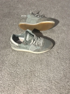 Grå sneakers i mocka och mesh - Säljer ett par grå sneakers med snygga detaljer i mocka och mesh. Skorna har snörning och en platt sula, samt rund tå. Perfekta till jeans och funkar året runt. Stilrena och lätta att matcha med olika outfits.