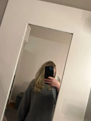 Grå stickad tröja från Vila - Mysig grå stickad tröja från Vila med markerad söm framtill och bred ribbad kant nedtill. Tröjan har lång ärm och en högre rundad halsringning. Perfekt för kyliga dagar och enkel att styla med jeans eller kjol. Lite noppig men syns knappt 