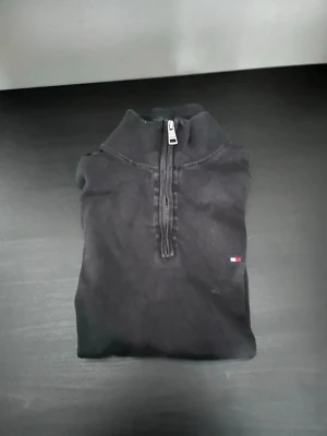 Svart half zip tröja Tommy Hilfiger - Svart långärmad tröja från Tommy Hilfiger med half zip-dragkedja. Köpt på Zalando för 1200kr men hann inte använda så mycket innan jag växte ur den. Mycket bra skick 