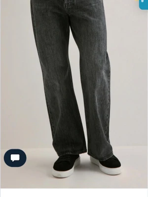 Svarta wide jeans med rak passform - Säljer ett par svarta jeans med tvättad look och breda ben. Jeansen har klassisk femficksdesign och raka sömmar. Perfekta för dig som gillar en avslappnad och trendig stil. Materialet är jeans och färgen är mörkgråsvart. Säljer då de va en julklapp som inte kunde lämnas tillbaka. STORLEK: W31/L34