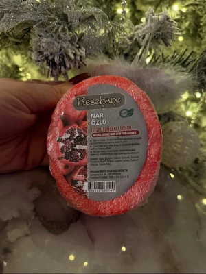 Kesehane granatäpple tvättsvamp - En oval, röd tvättsvamp med granatäppleextrakt från Kesehane. Produkten är inslagen i plast och har en naturlig svampstruktur. Perfekt för rengöring och exfoliering av huden, med en fräsch doft av granatäpple.
