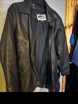 Svart skinnjacka från Newport XL - Säljer en svart skinnjacka från Newport i storlek XL. Jackan har klassisk krage, dragkedja framtill och flera fickor med dragkedjor. Perfekt för dig som vill ha en tidlös och cool look.