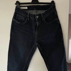 Mörkblå raka jeans från Zara - Säljer ett par mörkblå jeans från Zara med klassisk femficksdesign och raka ben. Jeansen har hög midja och stängs med knapp och dragkedja. Materialet är robust denim i bomull och passformen är normal. Perfekta till en avslappnad look.