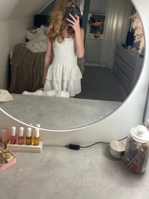 Vit klänning från RYVLS - Supersöt vit kortklänning från RYVLS med smockad överdel och dubbla volanglager i kjolen. Klänningen är ärmlös och har broderade spetsdetaljer som ger en romantisk vibe. Perfekt för sommarens alla tillfällen!🌷🤍💕 Priset är inte skrivet i sten och går att diskuteras.