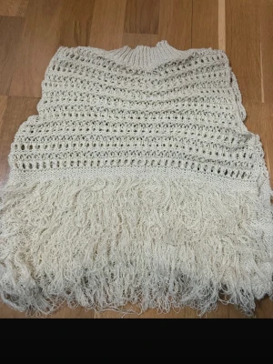 Beige stickad väst med fransar från SHEIN - Säljer en beige stickad väst från SHEIN i storlek S. Västen har ett öppet stickat mönster och coola fransdetaljer nedtill som ger en unik look. Perfekt att slänga över en långärmad tröja eller skjorta för extra stilpoäng.