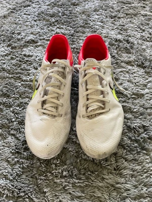 Nike Tiempo legend 9 PRO motivation pack forbollsskor - Nike Tiempo fotbollsskor i vitt skinn med gula och svarta detaljer samt röd insida. Skorna har snörning och dobbar i neonfärg för bästa grepp på planen. Perfekta för dig som vill sticka ut med stilren design och grym komfort. Pris ej hugget i sten.