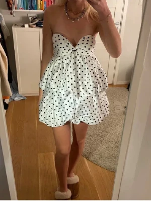 Super snygg volangklänning - Supersöt vit kort klänning med svarta prickar och volanger. Axelbandslös modell med hjärtformad urringning och markerad midja. Perfekt för dig som vill sticka ut med en lekfull och trendig look. ❗️Stor i bysten så man har det i baktanken❗️