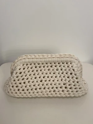 Handvirkade Clutch Väska i benvit  - Vi är ett UF-företag som säljer handvirkade Clutchväskor! 🩷 Denna väska är i färgen benvit. Väskan har en unik form och känns både trendig och handgjord. Perfekt för dig som gillar en personlig touch på din outfit. OBS‼️ KÖPAREN STÅR FÖR FRAKTEN 