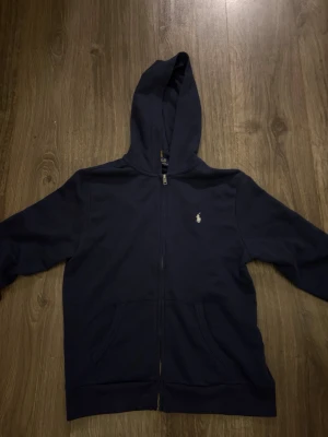 Mörkblå hoodie från Polo Ralph Lauren - Mörkblå hoodie med dragkedja från Polo Ralph Lauren. Använd endast tre gånger. Storlek 14-16 år