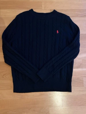 Ralph Lauren Cable knit - Säljer en svart cable knit från Polo Ralph Lauren i storlek S. Den är som ny och har mycket kvar att ge. Hör av dig vid minsta fundering!