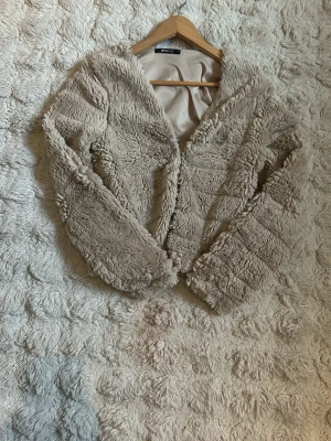 Beige fluffig kofta från Gina tricot - Supersnygg beige fluffig kofta från Gina tricot med mjukt foder och långa ärmar. Koftan har en öppen design och är gjord i ett lurvigt material som ger en lyxig känsla. Perfekt för dig som vill ha något både mysigt och trendigt.❤️