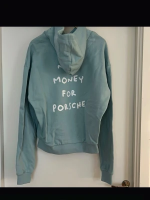 Blå hoodie med tryck 'Need Money for Porsche' - Ljusblå hoodie Emil Stegfeldts limited hoodie han släppte 2022 som inte kommit till användning. Nummer 28 av 120 stycken sålda.  Storlek M