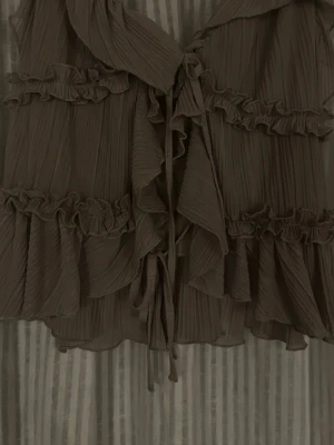 Grå volangblus med knytband - Supersnygg brun blus med volanger och knytband framtill. Plisserad struktur och flera lager. Perfekt att styla med jeans eller kjol. Använts ett fåtal gånger i väldigt bra skick❣️