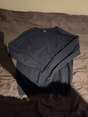 Mörkblå stickad tröja från Oscar Jacobsson  - Mysig mörkblå stickad tröja från oscar Jacobsson med rund halsringning och långa ärmar. Tröjan har en klassisk och stilren design i mjukt material. Använd max 5 gånger