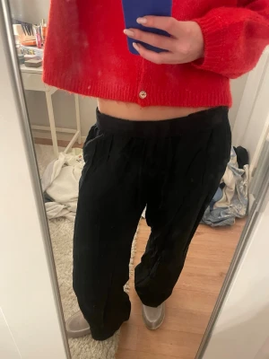 Svarta linnebyxor med loose fit - Snygga svarta linnebyxor med avslappnad passform och resår i midjan. Byxorna har raka ben och är perfekta för en chill och stilren look. Tillverkade i linne för en luftig känsla.