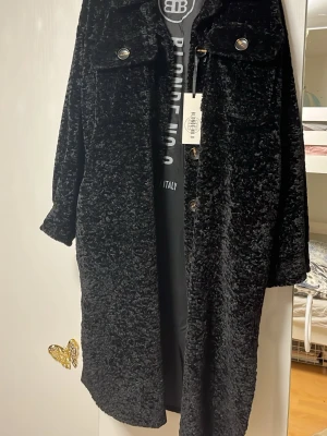 Svart teddyrock från Blonde No.8 - Snygg svart teddyrock från Blonde No.8 med stora knappar framtill och två bröstfickor. Rocken har en mjuk och fluffig textur som ger en trendig look. Perfekt för dig som vill ha en statementjacka med oversized känsla. Ny och superfin!!!!!!!!!!! Passar bäst om du har storlek M-XL.