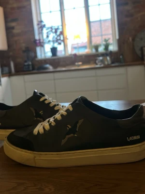 Svarta arigato skor  - Säljer ett par svarta sneakers från 140MM med vit sula och vita snören. Skorna har ett coolt fågeltryck på sidan och en stilren design som passar till det mesta. Materialet känns som skinn och sulan är platt för skön komfort. Pris kan diskuteras!