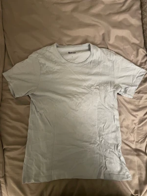 Ljusblå t-shirt från BOSS - Snygg vit t-shirt från BOSS med diskret broderad logga på bröstet. Klassisk passform och rund halsringning, perfekt till jeans eller shorts. Tillverkad i mjuk bomull som känns skön mot huden.