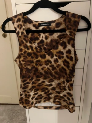 Leopardmönstrad linnetopp från Only - Säljer en snygg leopardmönstrad linnetopp från Only med v-ringad hals och breda axelband. Toppen har en figurnära passform och är tillverkad i ett mjukt syntetmaterial som känns skönt mot huden. Perfekt för dig som vill sticka ut med djurprint! Står inte strl men sitter som s