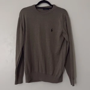 Beige tröja från Polo Ralph Lauren - Snygg beige tröja från Polo Ralph Lauren med klassisk rund hals och diskret logga broderad på bröstet. Tröjan är tillverkad i 100% bomull och har långa ärmar samt ribbade muddar vid hals, ärmslut och nederkant. Perfekt för en chill och stilren look. Storlek M funkar för L också! Pris kan diskuteras.