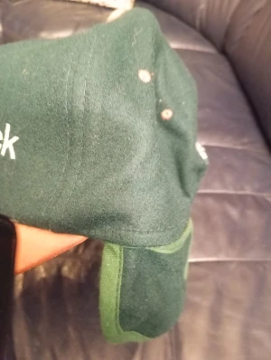 Grön Timberjack keps - Snygg keps från Timberjack med mörkgrön ovandel och brun skärm i mocka-look. Framtill är märket broderat i vitt. Klassisk form med rundad skärm och knapp på toppen. Perfekt för dig som gillar outdoor-vibe och vill sticka ut med en unik färgkombo.