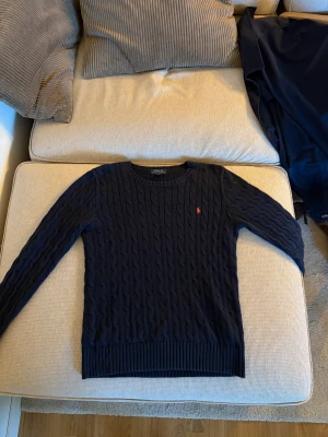 Mörkblå stickad tröja från Polo Ralph Lauren - Snygg mörkblå stickad tröja från Polo Ralph Lauren.  Storlek L i barn storlek, så ungefär xs 