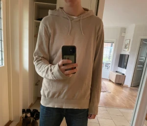 Hoddie från Strömberg - Snygg beige hoodie från Strömberg i ekologisk bomull. Tröjan har huva med snörning och ribbade muddar vid ärmslut och nederkant. Perfekt för chill dagar och enkel att matcha med jeans