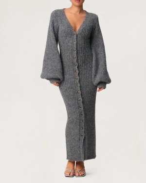 Adoore Montana Maxi Dress Grå - Supermysig lång stickad figyrsydd klänning från Adoore i grått med ribbad struktur. Klänningen har v-ringning, ballongärmar och knappar hela vägen framtill. Har endast använts fåtal gånger och är utan defekter.