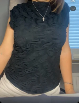 Svart strukturerad topp med hög hals från zara - (FRÅN ZARA) Säljer en svart topp med coolt strukturerat tyg och hög hals. Toppen är ärmlös och har en slim passform som sitter snyggt mot kroppen. Perfekt för dig som gillar stilrena plagg med lite edge. Fråga gärna om fler bilder eller mått!