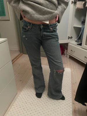 Weekday jeans - Säljer ett par relativt straight/ bootcut jeans från weekday med hål på knät och där uppe. Storleken är: w27, L32.            midjemåttet är ca 40cm, och innerbensmåttet 75cm. Min syrra på bilden är ca 163