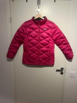 The North Face  - Quiltad pufferjacka från The North Face i en snygg rosa färg. Jackan har dragkedja framtill, två sidofickor med dragkedja och justerbara muddar med knapp. Perfekt för kalla dagar och har en cool, sportig vibe.  Pris kan diskuteras. Skicks gärna, bud. 