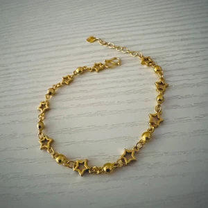 Guldigt armband med stjärnor - Snyggt armband i guldton med små stjärnformade länkar och runda pärlor. Justerbar längd med kedja och karbinlås. Perfekt för dig som gillar detaljer med lite extra glans och unik form.