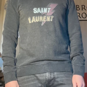 Saint Laurent sweatshirt Bolt - Grå sweatshirt från YSL Saint Laurent med ”Bolt” blixt- och logotryck på bröstet. Storlek: M men sitter mer som S. (Jag är 176 och den sitter rätt bra på mig.)