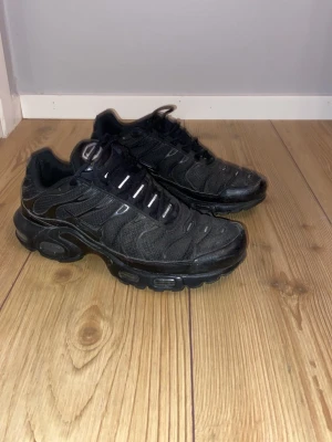 Nike Tn svarta sneakers - Nike Tn sneakers i helsvart med TN-logga på hälen och sulan. Skorna har en chunky, vågig design med mesh och syntetpaneler, snörning och robust gummisula. Ganska använda men ändå i bra skick. Perfekt för dig som gillar streetwear och sportig stil. Är öppen för förhandling vid snabb affär. Nypris: 2300kr