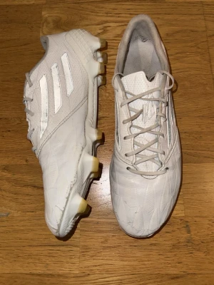 Vita Adidas F50 fotbollsskor i läder, stl 41 1/3 - Säljer ett par väldigt limiterade Adidas F50 fotbollsskor i läder. Lädret är av högt kvalité och väldigt mjukt, samtidigt som skorna fortfarande är väldigt lätta. Otroliga fotbollsskor! Storlek 41 1/3. Slutsålda överallt, och finns numera endast på andrahandsmarknaden. Normalt slitage från sporadiskt användande. Priset är aningen förhandlingsbart.