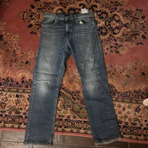 Replay Thad jeans 16A – blå med slitningar - (80) Snygga blå Replay Thad jeans i storlek 16A med en riktigt clean och unik slitning på benet. Klassisk femficksdesign och slim passform som sitter perfekt. Perfekta för dig som gillar en modern och trendig jeanslook. Midja 37cm längd 93cm #Replay #ReplayJeans #Thad #SlimFit #Denim #SlitnaJeans #Trendig #Herrmode #SnyggaJeans #OutfitInspo