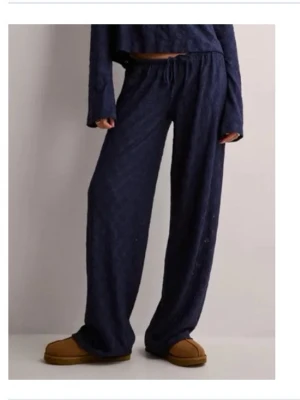 Mörkblå mjukisbyxor med snörning - Säljer ett par mörkblå mjukisbyxor med breda ben och snörning i midjan. Byxorna har en loose passform och är perfekta för en chill och avslappnad stil. Materialet är mjukt och bekvämt, perfekt för att hänga hemma eller dra till kompisar. Helt oanvända🥰